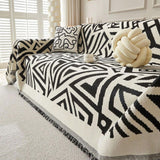 Sofa with a black and white patterned throw blanket and decorative knot pillow.